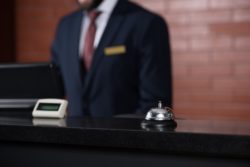 close up of a hotel reception desk bell and staff person