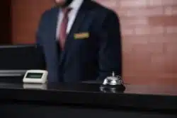 close up of a hotel reception desk bell and staff person