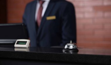 close up of a hotel reception desk bell and staff person