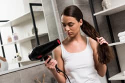 woman using blow dryer looking displeased