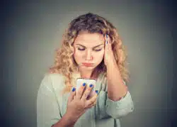 Woman looking down at phone annoyed