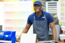 A male cashier greets customers at the retail outlet's check-out lane.