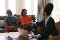 Woman shakes hand with wife of couple learning about insurance
