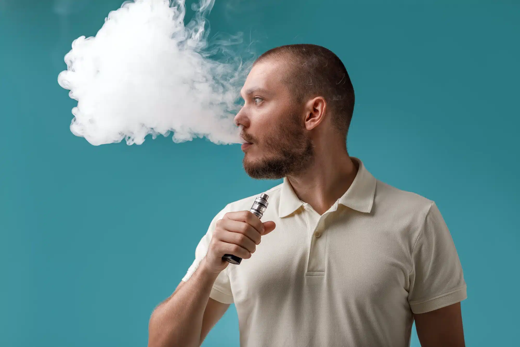 Man looks to his right and blows vape cloud.