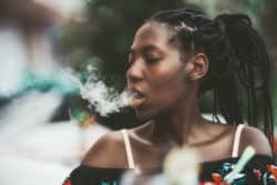 Young woman exhales vape cloud