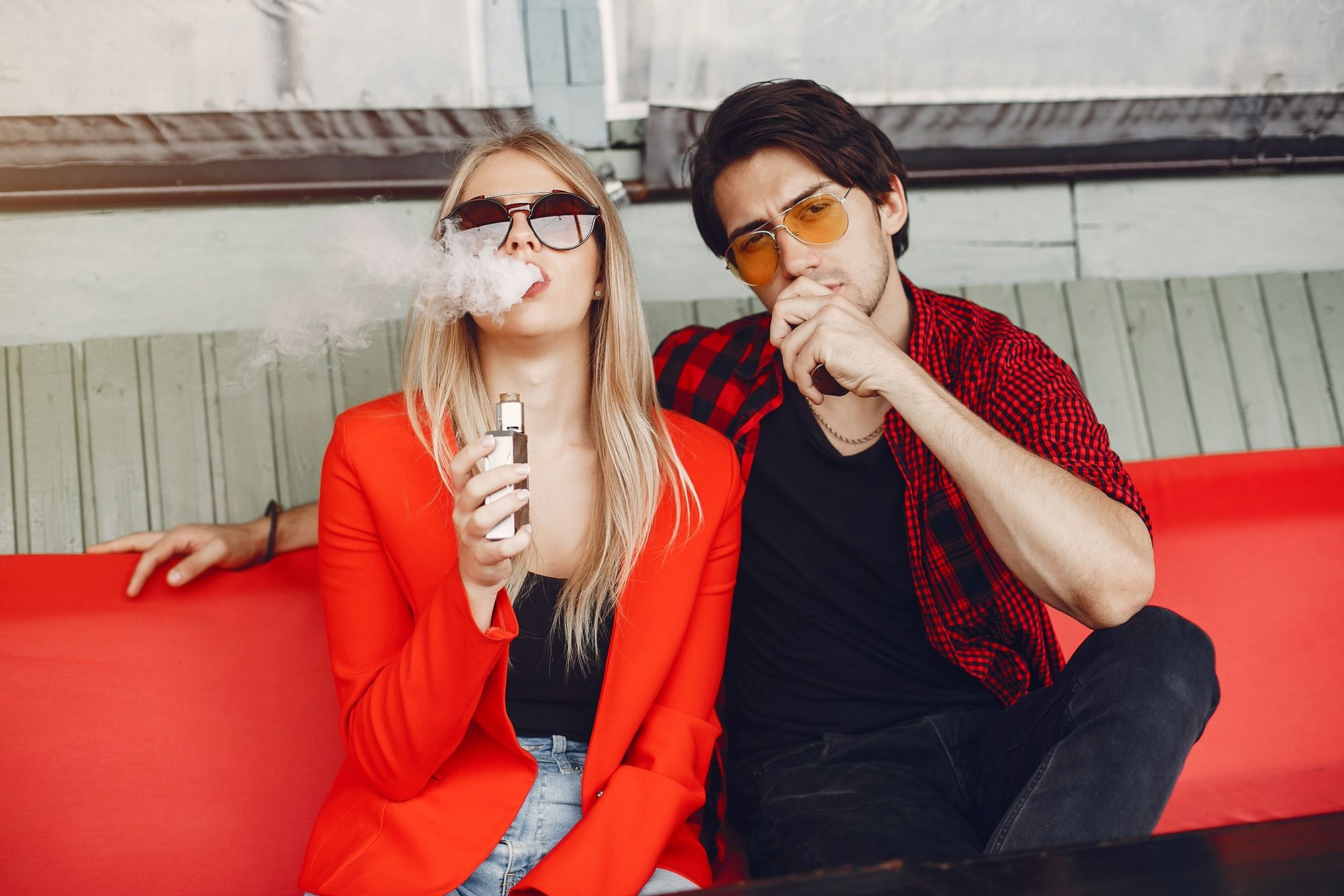 A couple sits and vapes.