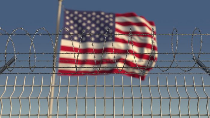 american flag set behind barbed wires is what migrant families are seeing during the coronavirus outbreak