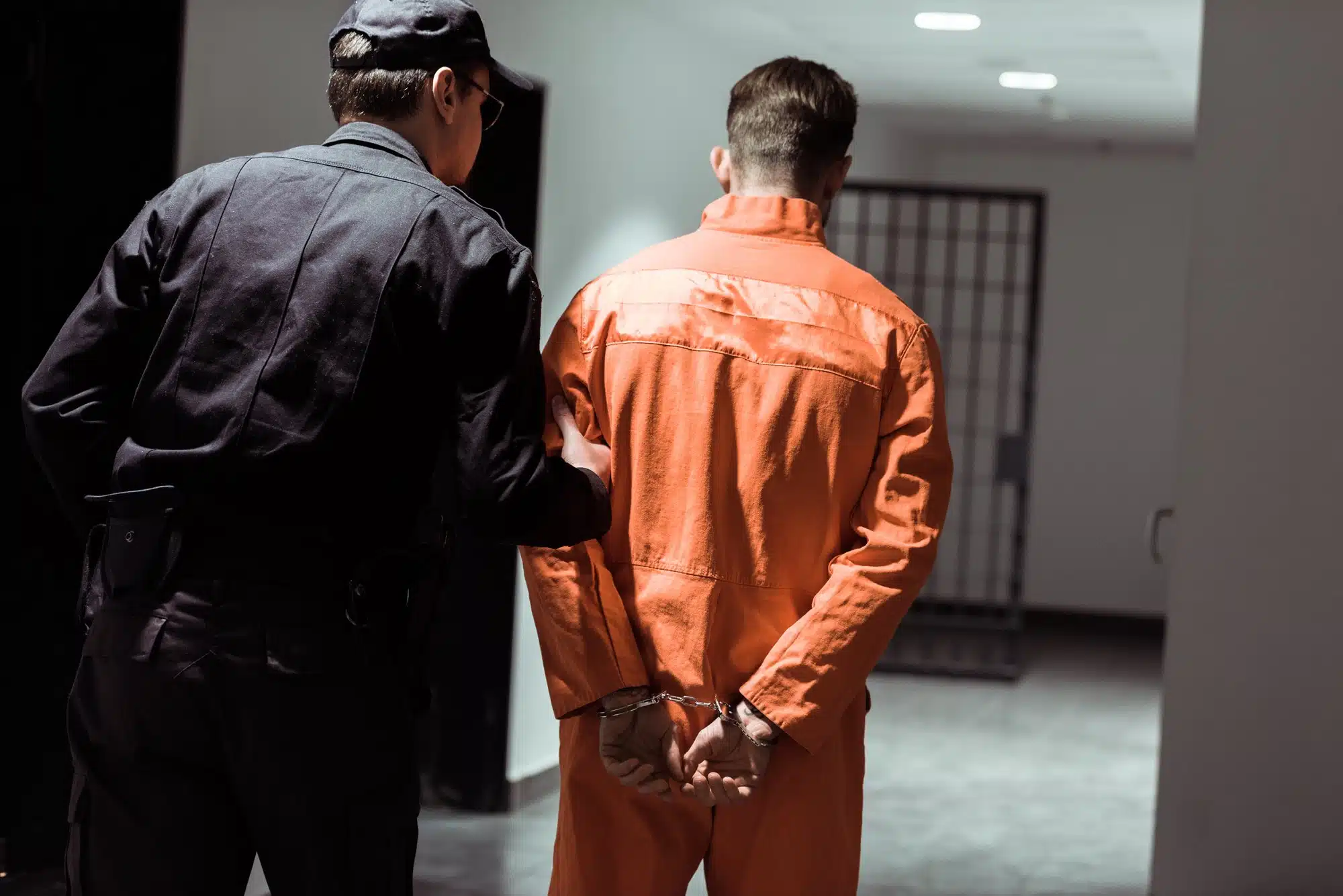 A guard leads an inmate down a hall.