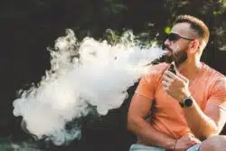man vaping and exhaling smoke