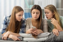 Teen girls on cell phone looking confused and upset