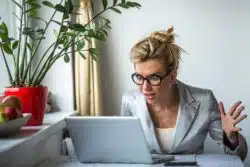 Woman looking confused and upset at her computer regarding the class action lawsuit against Cheapoair accusing them of charging customers undisclosed fees