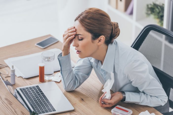 New Jersey businesswoman working at her desk while being sick