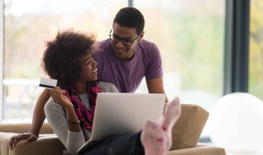 Young couple shops online with debit card in hand