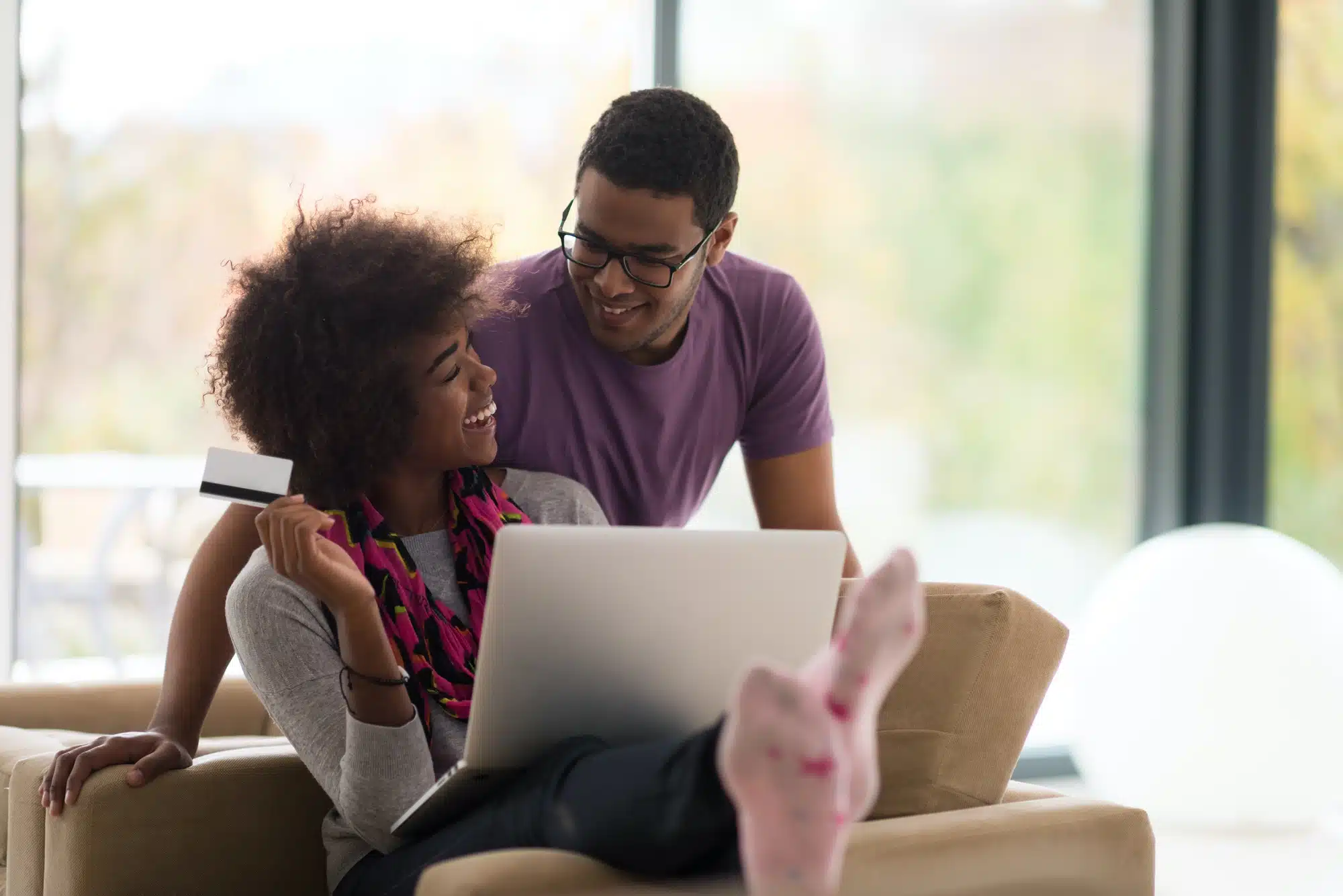 Young couple shops online with debit card in hand