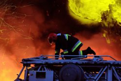 Large building fire with fireman on truck