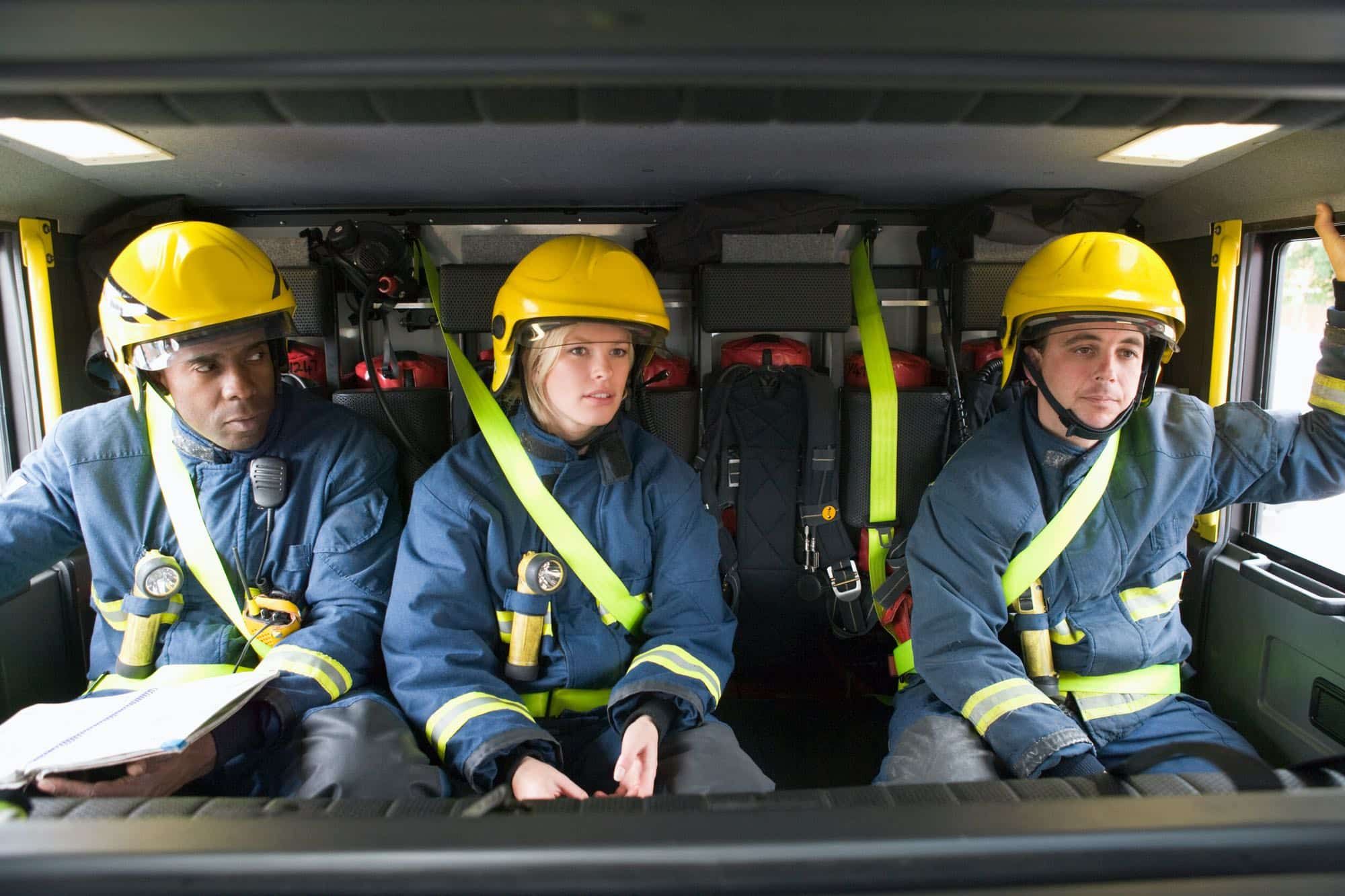 Three firefighters sit in fire truck on way to emergency scene
