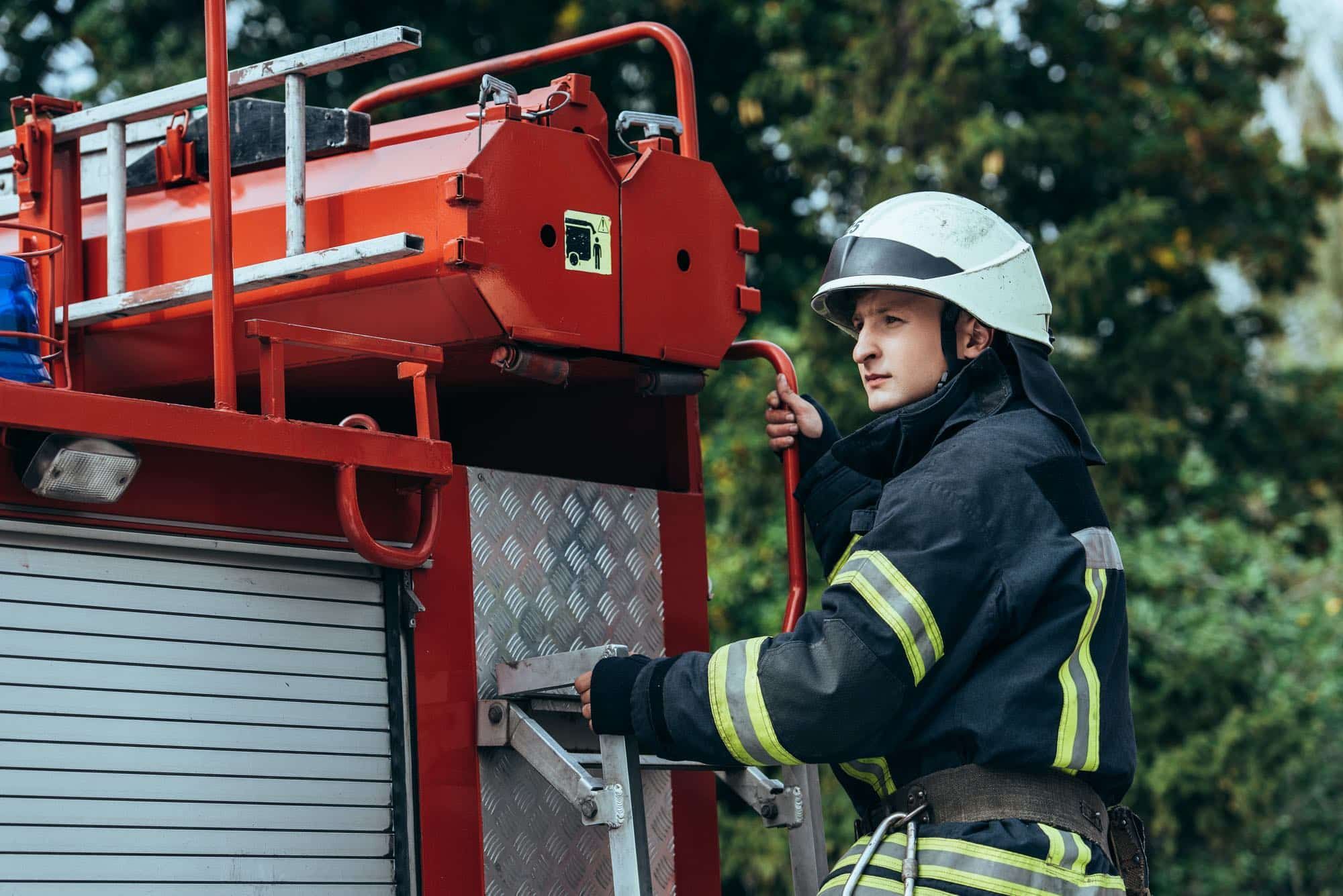 Male firefighter stands on fire truck