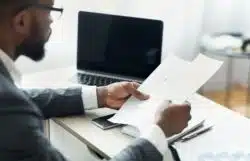 Man at desk with computer reviews financial papers