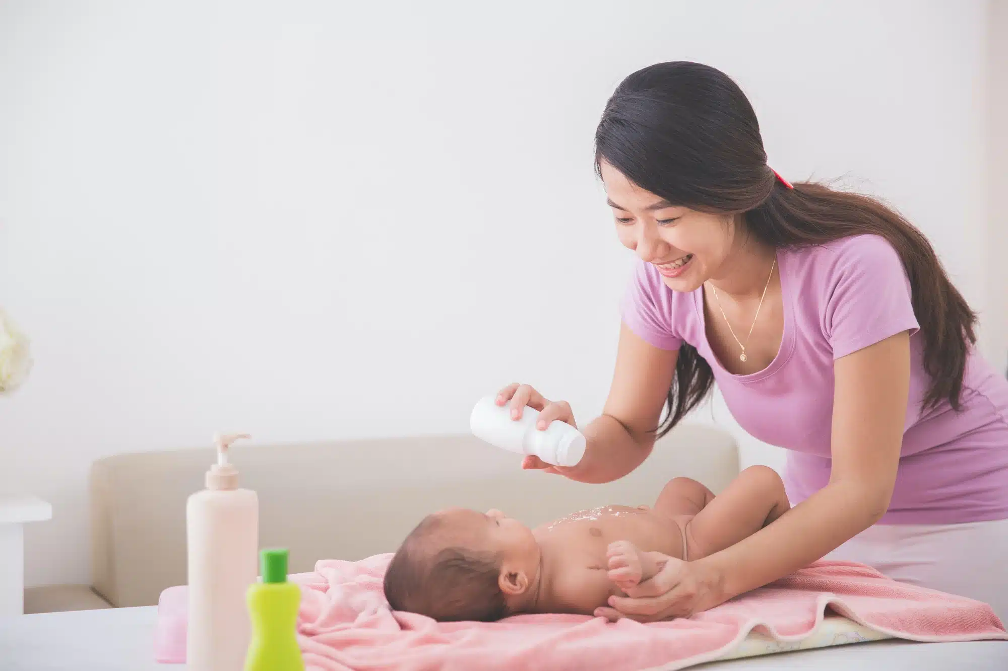 Mother sprinkles powder on baby's tummy