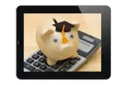 Piggy bank wears graduation cap and sits atop calculator