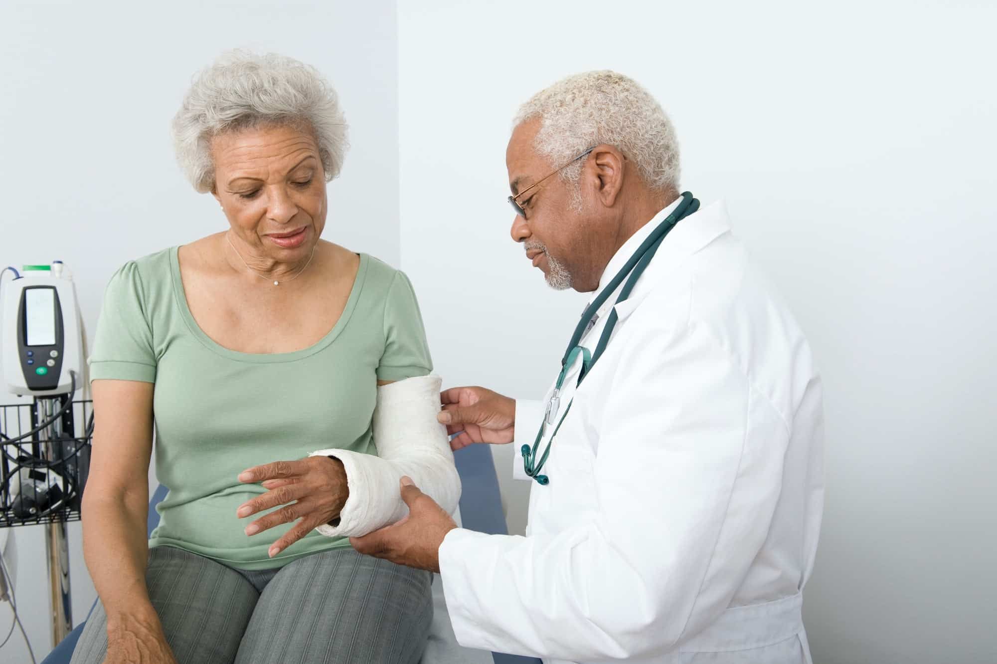 Doctor looks at cast on arm of elderly woman