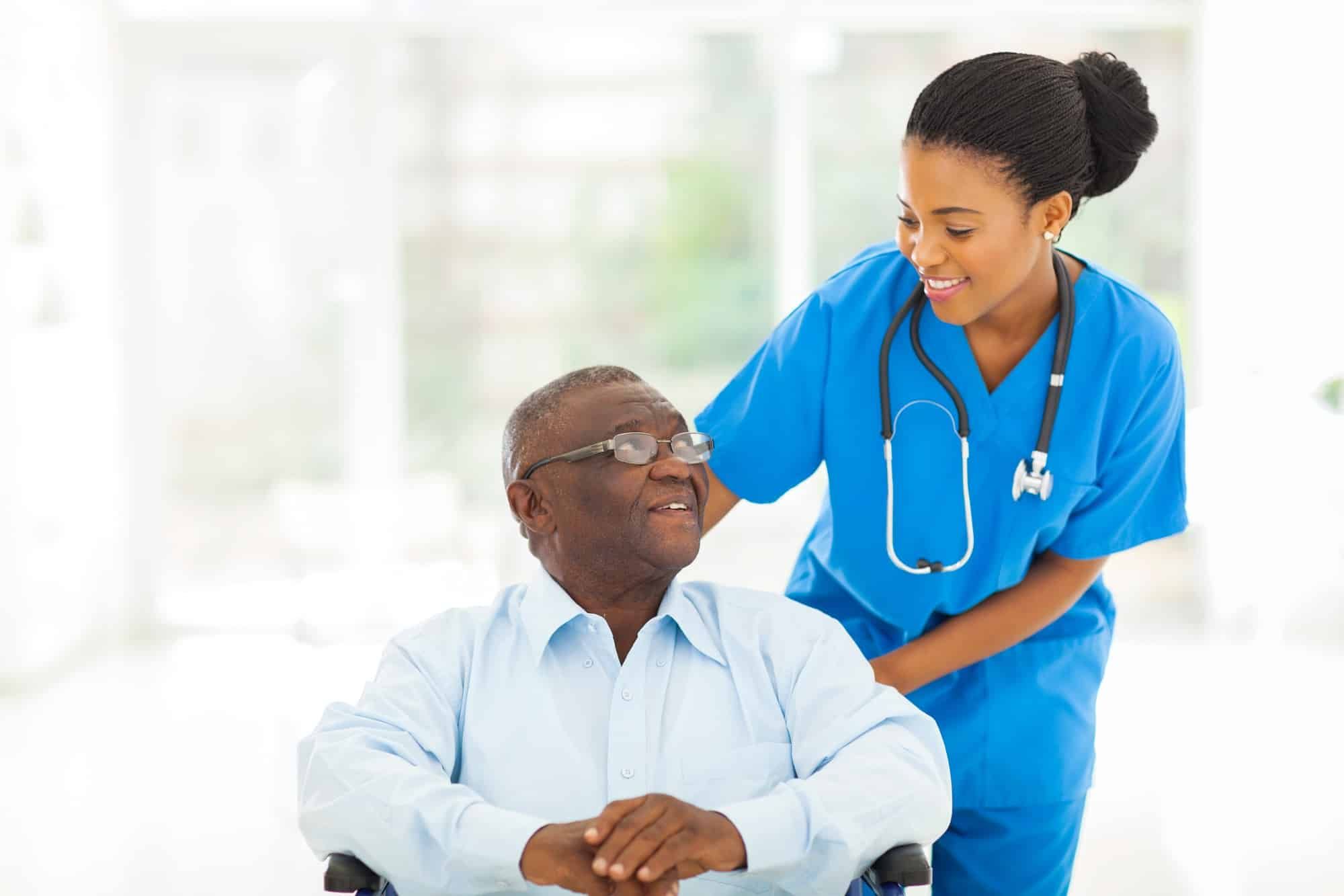 Female doctor talks to male patient in wheelchair