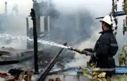 firefighter spraying ruins after fire