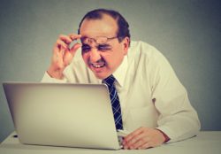 man with eye issues looking at laptop