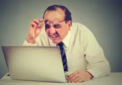 man with eye issues looking at laptop
