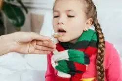 Mom gives spoonful of medicine to daughter.