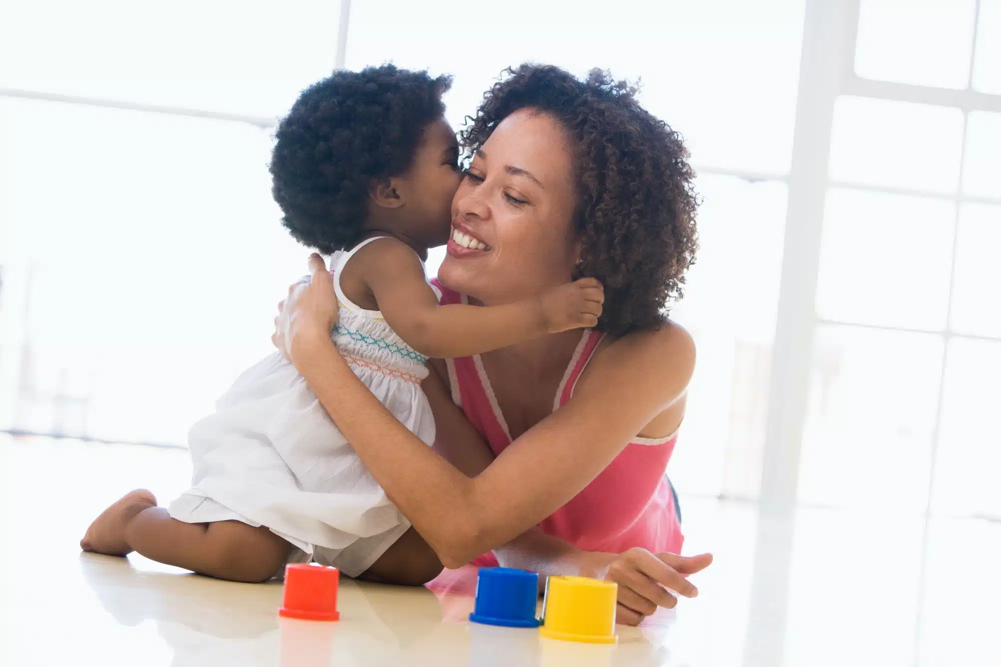 Mom hugs baby daughter playing with colorful blocks