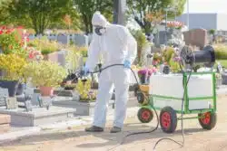 gardener wearing protective gear while spraying roundup