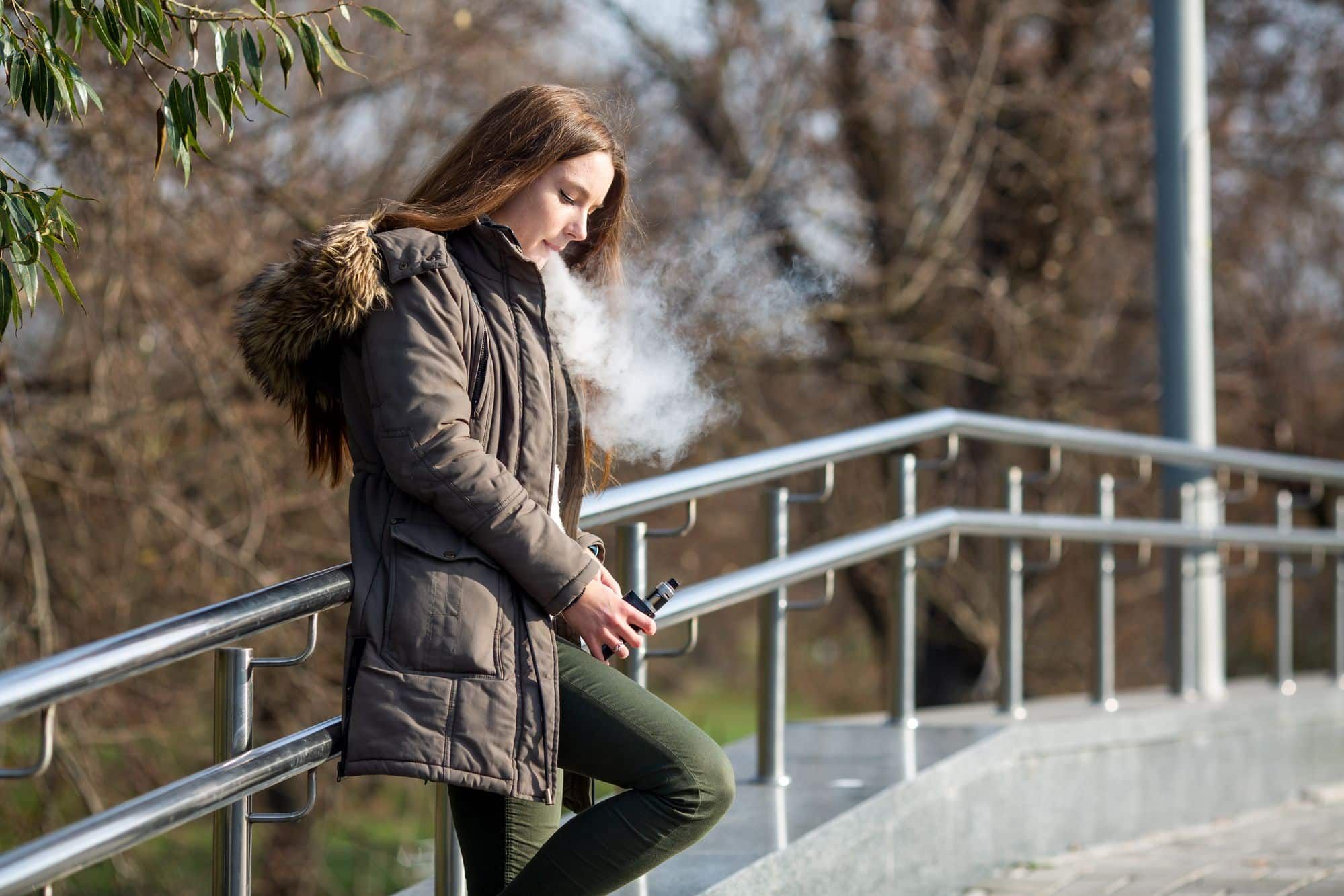 teenager smoking e-cigarette on campus steps