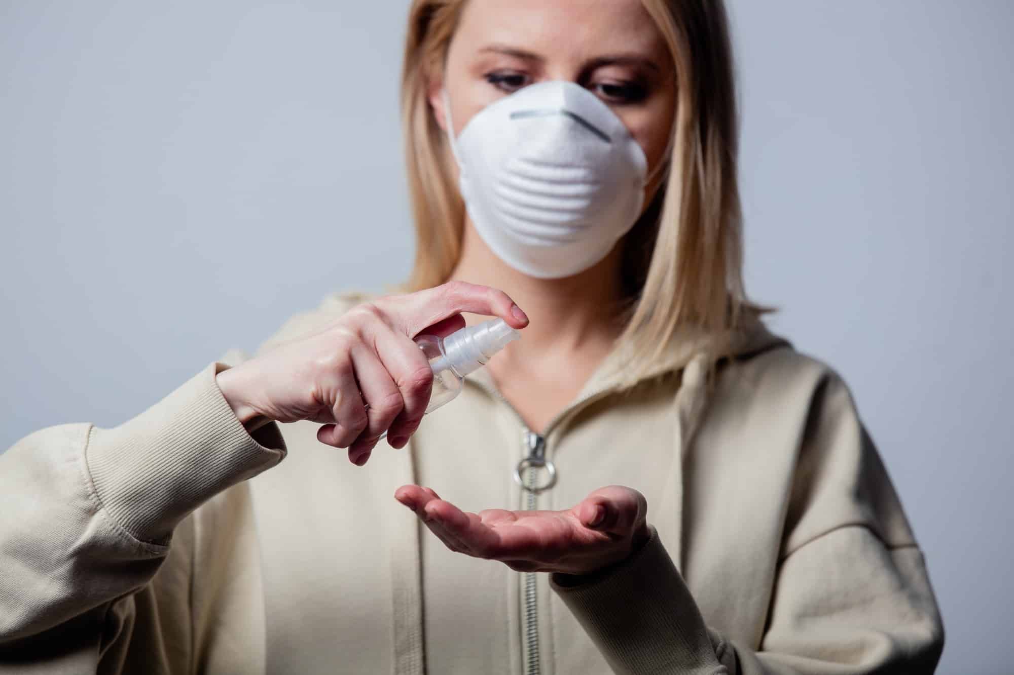 woman with protective mask uses hand sanitizer