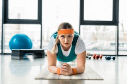 A woman planks in a gym.