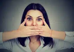 young woman holding hands over mouth