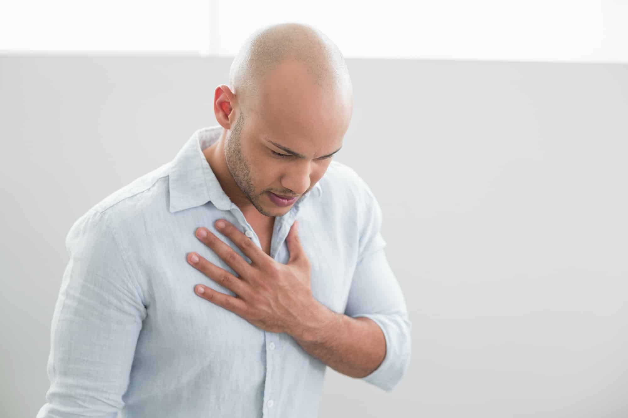Yong man with heartburn holds his chest 