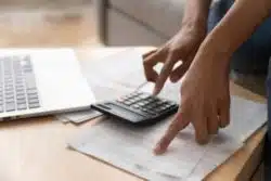 Closeup of one hand on invoice and one hand on calculator