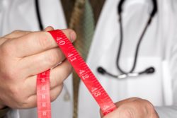 Doctor holds out red measuring tape
