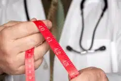 Doctor holds out red measuring tape