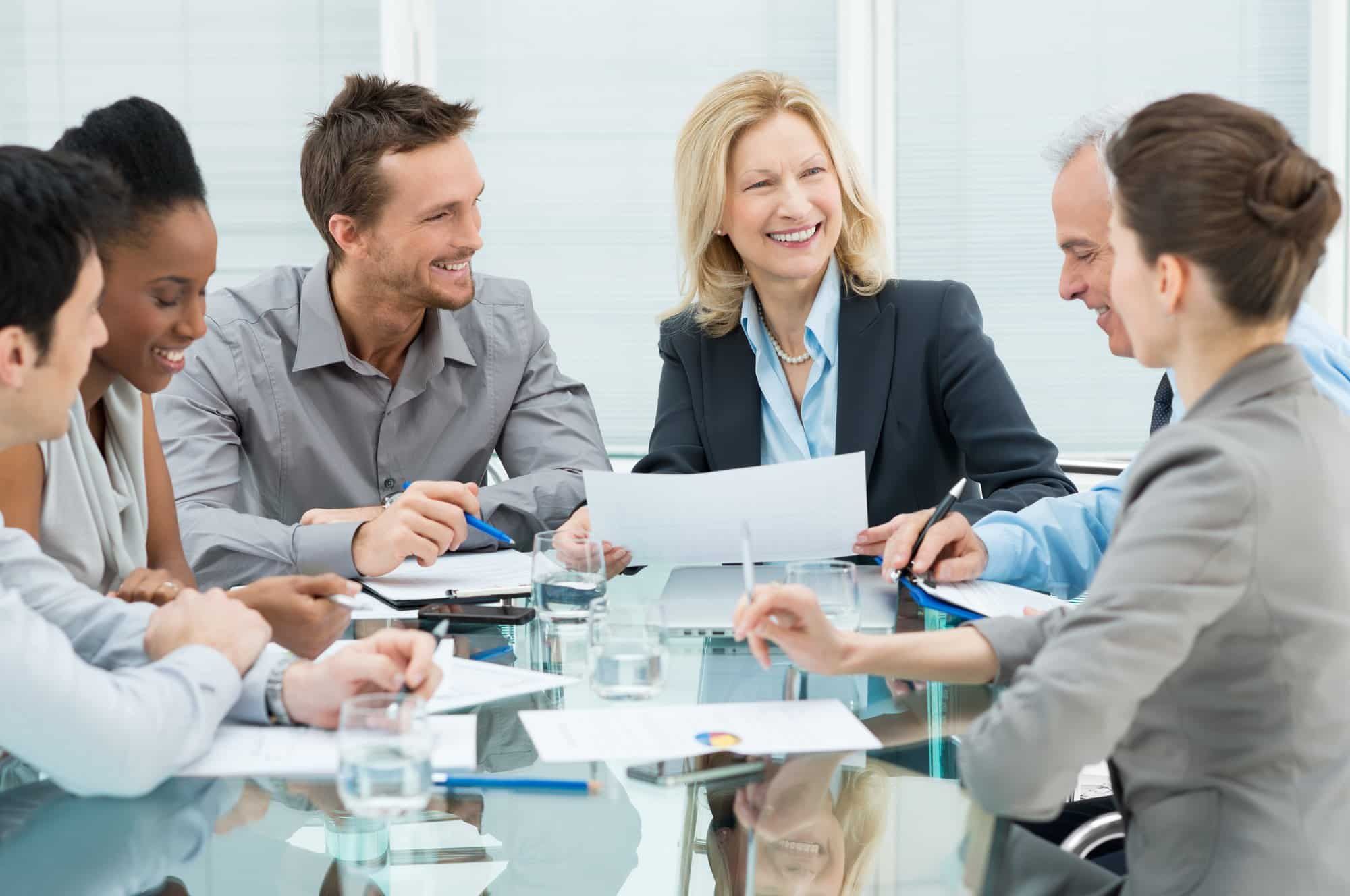 Older and younger employees work at a table.