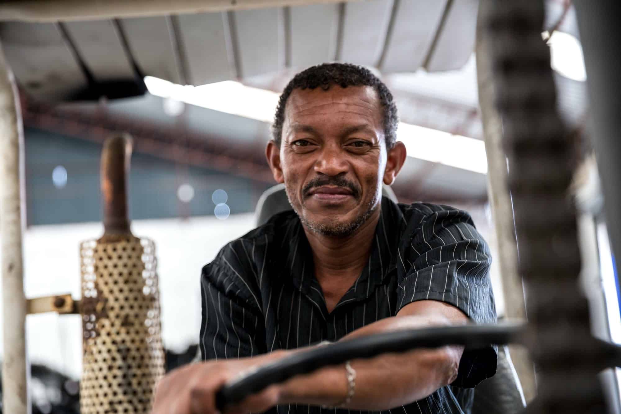 Older male employee sits on forklift and looks at camera