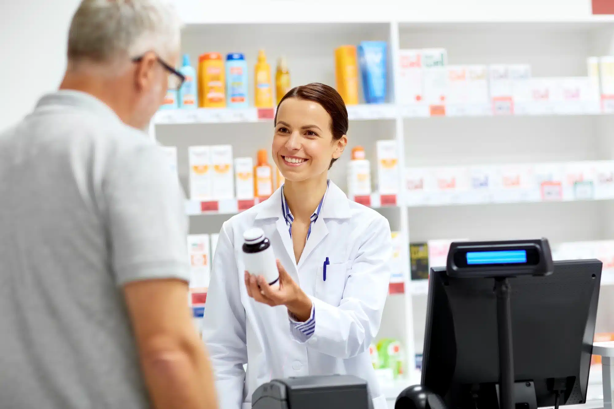 A pharmacist hands a jar to a customer.