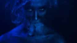 Woman vaping lit by dark blue light