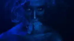 Woman vaping lit by dark blue light