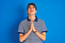 Distressed teen boy looks up and prays