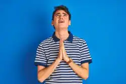 Distressed teen boy looks up and prays
