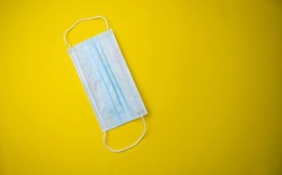 Medical face mask on yellow background