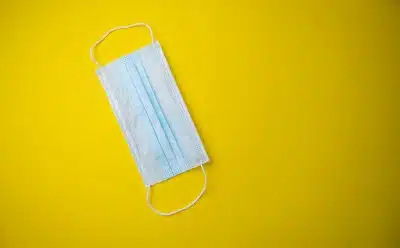 Medical face mask on yellow background