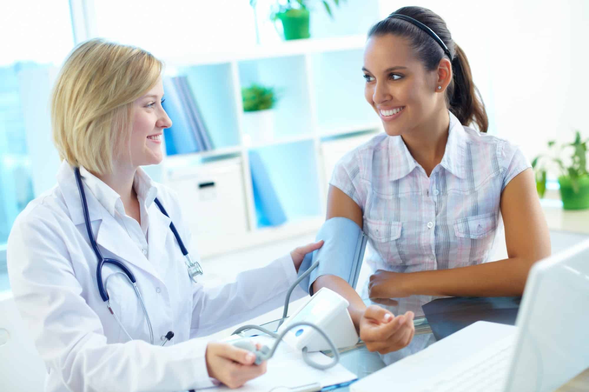 Female doctor takes blood pressure of female patient